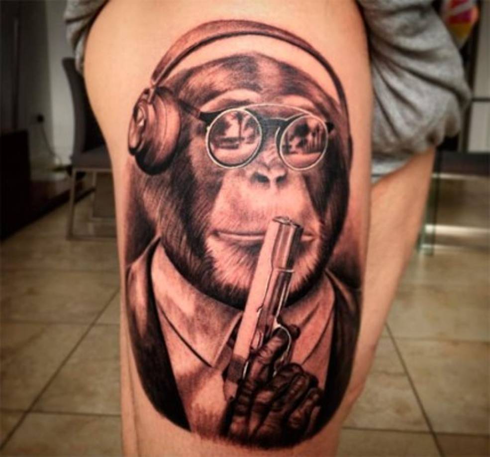 El español Alberto Moreno en el muslo derecho tiene la imagen de un mono con gafas de sol, auriculares y una pistola.