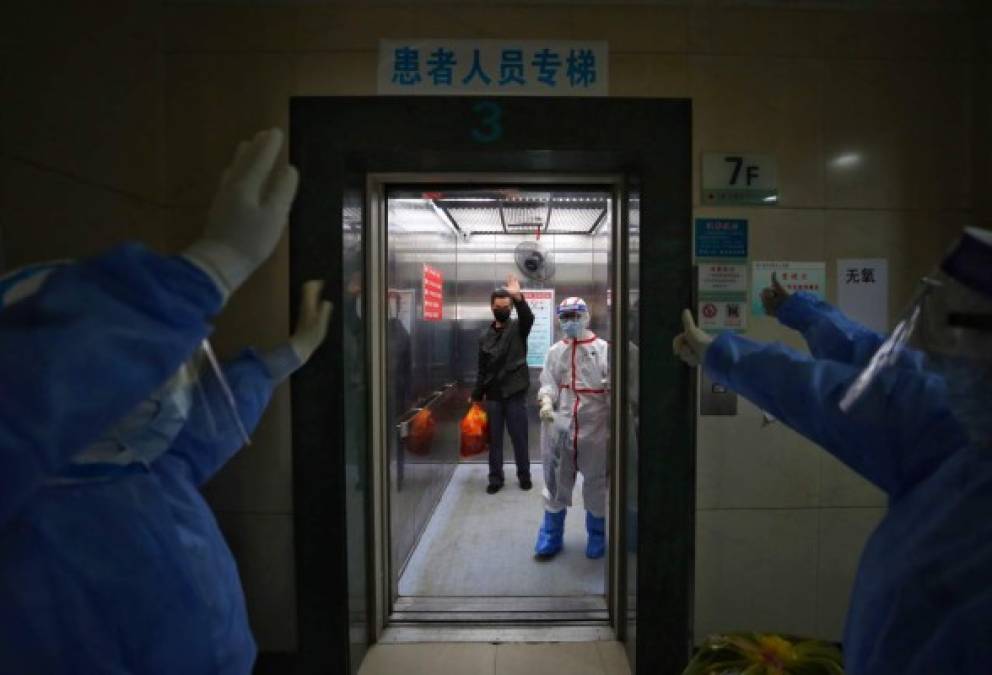 Medical staff wave goodbye to a recovered COVID-19 coronavirus patient at the Red Cross Hospital in Wuhan in China's central Hubei province on March 16, 2020. - China reported 12 more imported cases of the novel coronavirus on March 16 as the capital tightened quarantine measures for international arrivals to prevent a new wave of infections. (Photo by STR / AFP) / China OUT