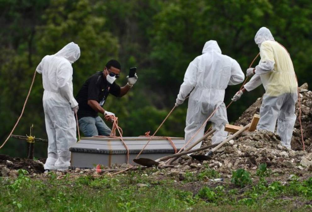 Un hombre filma con un teléfono móvil mientras ayuda a enterrar a una víctima de COVID-19 en un cementerio en las afueras de Tegucigalpa durante la nueva pandemia de coronavirus. AFP