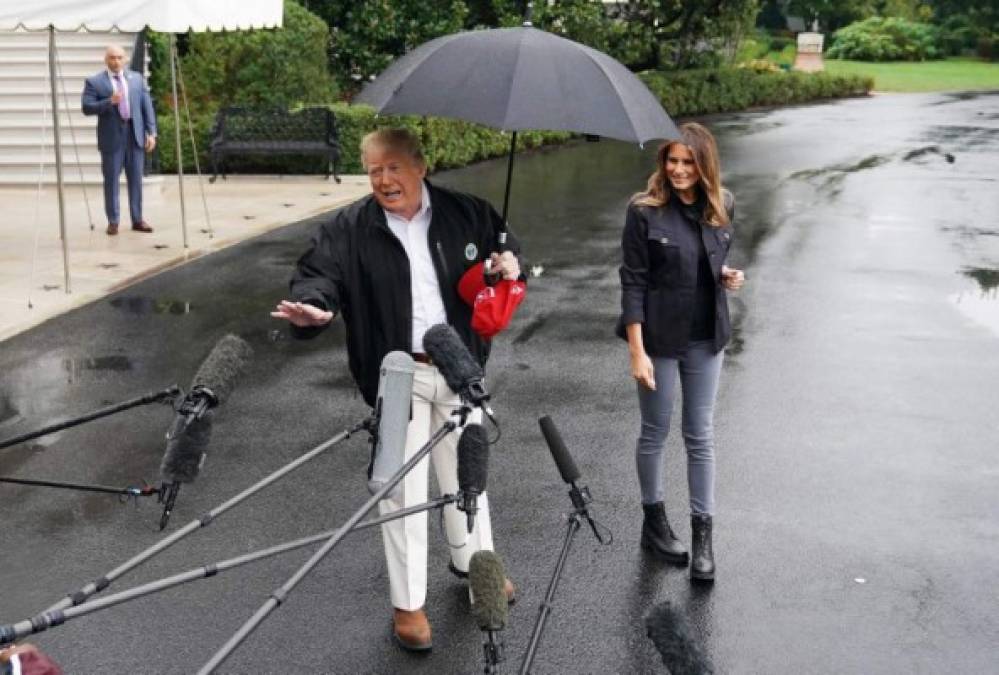 Trump dio declaraciones por varios minutos protegiéndose de la lluvia con un paraguas mientras su esposa lo esperaba pacientemente.