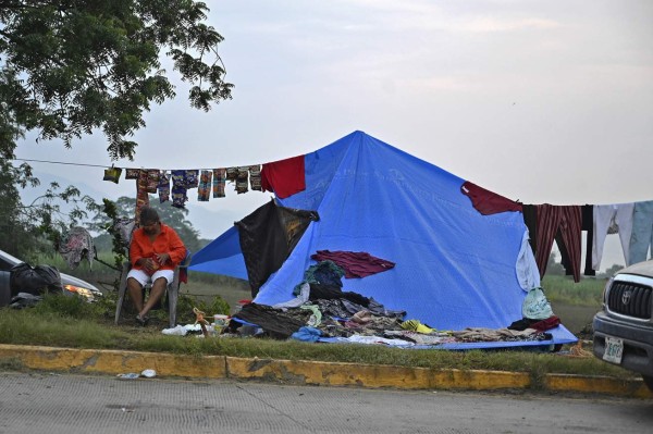 A woman sits outside an improvised tent after the passage of Hurricane Eta, later downgraded to Tropical Storm, in the municipality of La Lima, department of Cortes, Honduras, on November 10, 2020. - Fifty-seven people have died and eight are missing in Honduras following Tropical Storm Eta, authorities said Monday, as the death toll doubled in one of the countries worst hit by the storm. Eta slammed into Central America last week as a Category 4 hurricane, leaving over 200 people across the region dead or missing. (Photo by Orlando SIERRA / AFP)
