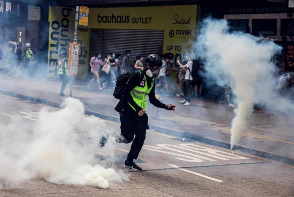 TOPSHOT - Police fire tear gas on protesters during a planned protests against a proposal to enact a new security legislation in Hong Kong on May 24, 2020. - The proposed legislation is expected to ban treason, subversion and sedition, and follows repeated warnings from Beijing that it will no longer tolerate dissent in Hong Kong, which was shaken by months of massive, sometimes violent anti-government protests last year. (Photo by ISAAC LAWRENCE / AFP)