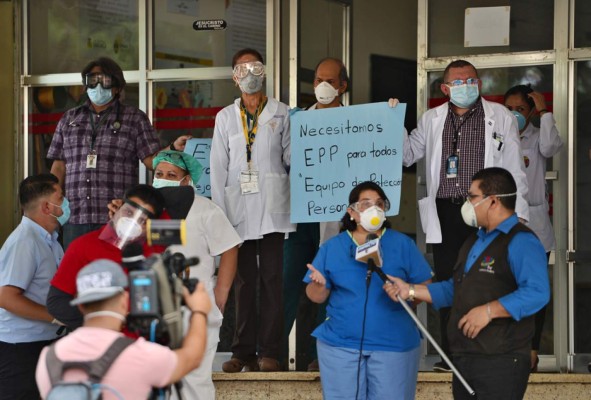 Doctors hold a sign reading 'We Need PPE for Everyone' as doctors and nurses of the School Hospital protest against their working conditions and demand personal protective equipment to prevent being infected by the novel coronavirus COVID-19, in Tegucigalpa on April 13, 2020. - The novel coronavirus is 10 times more deadly than swine flu, which caused a global pandemic in 2009, the World Health Organization said Monday, stressing a vaccine would be necessary to fully halt transmission. (Photo by Orlando SIERRA / AFP)