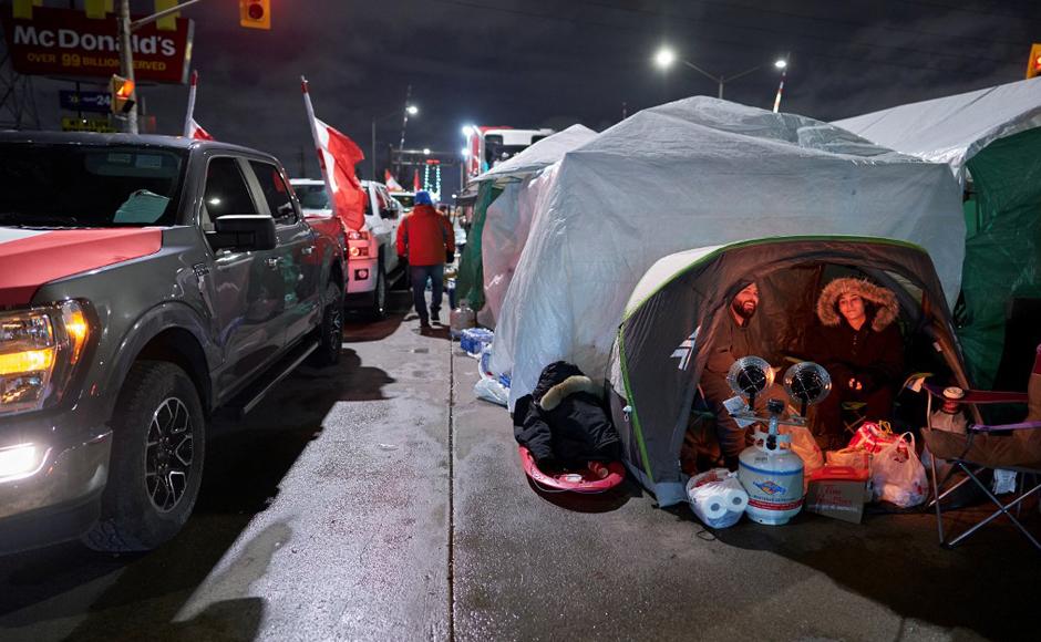 Los manifestantes contra el mandato de la vacuna se mantienen con un calentador en una carpa cuando salieron durante la noche en su barricada frente al cruce fronterizo del Puente Ambassador, en Windsor, Ontario.