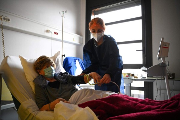 A French nurse tends to a patient infected with Covid-19 amidst the novel coronavirus pandemic at the Croix-Saint-Simon Hospital in Paris on March 5, 2021. (Photo by Anne-Christine POUJOULAT / AFP)