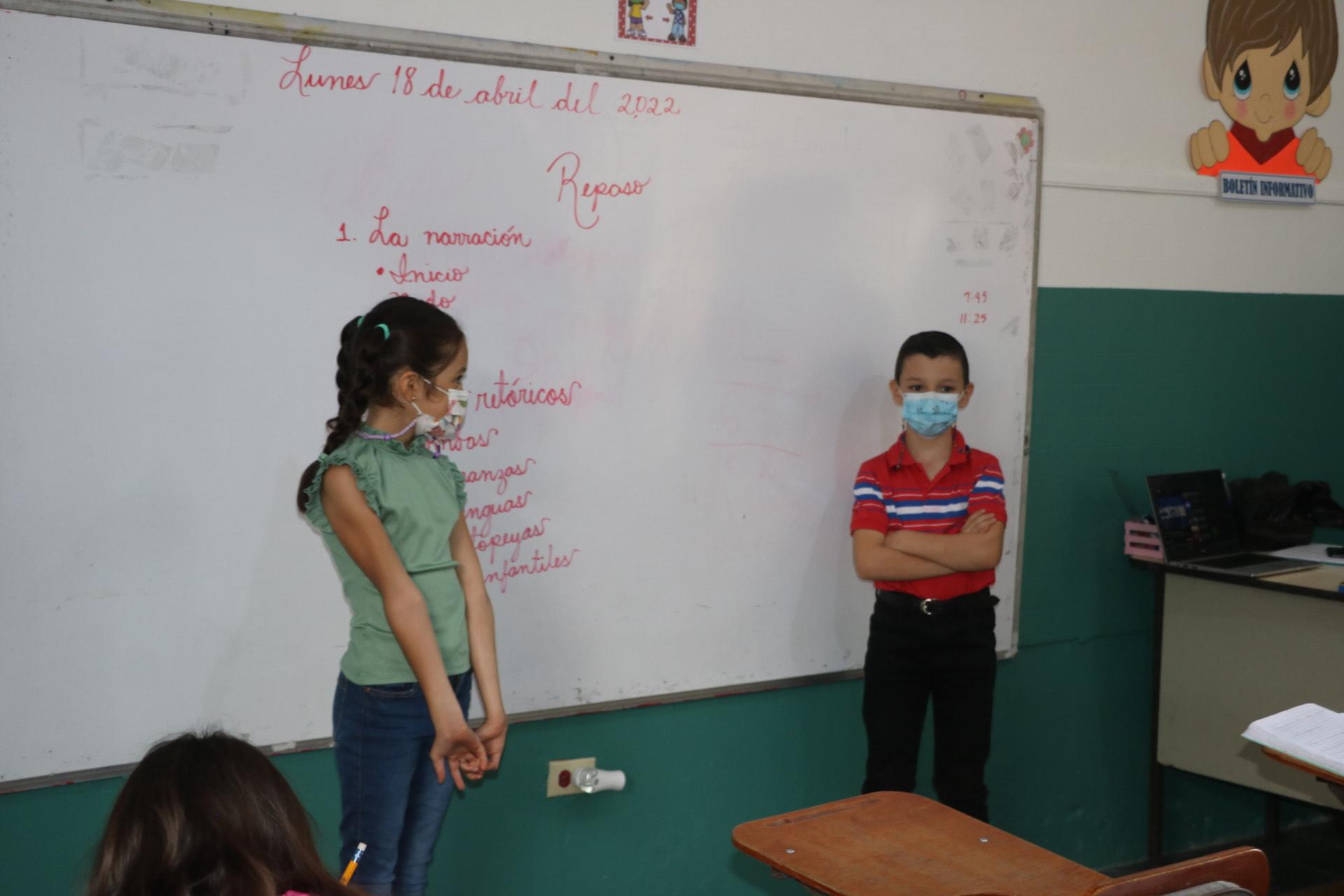 Dos escolares realizan una presentación durante el regreso a clases.
