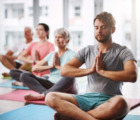 Cropped shot of a group of people meditating while practicing yoga