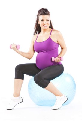 'Pregnant woman sitting on a workout ball after her workout, isolated on white background.'