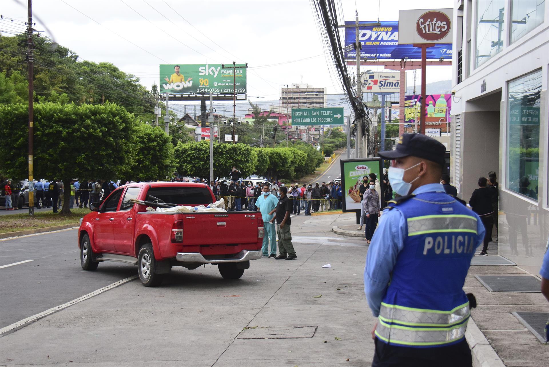 Policías y expertos forenses realizan el levantamiento de cuatro personas asesinadas en la madrugada de hoy, a la salida del estacionamiento de un edificio donde funcionan locales comerciales y residenciales, en Tegucigalpa (Honduras).