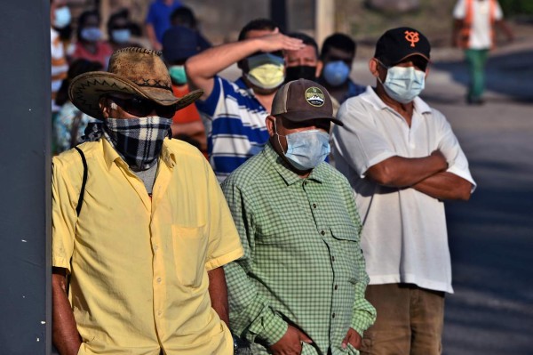 People wear face masks against the spread of the new coronavirus as they queue in a street of Tegucigalpa, on April 6, 2020. - The Honduran National Risk System (SINAGER) confirmed 30new cases of COVID-19, reaching a total of 298 cases in the Central American nation. (Photo by ORLANDO SIERRA / AFP)