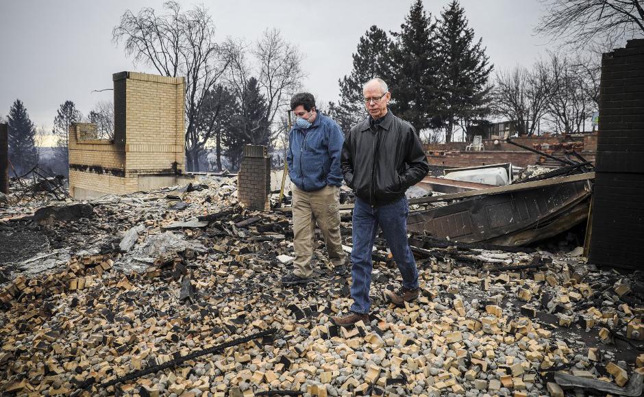 Los vecinos Louie Delaware (izquierda) y Roy Nelson caminan entre los escombros de la casa de Delaware después del incendio Marshall en Louisville, Colorado.