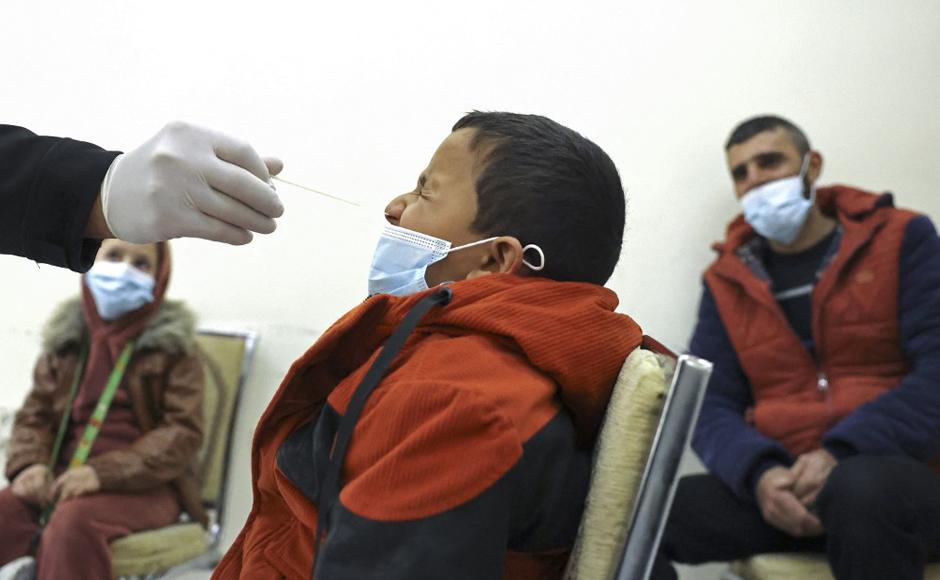 Un trabajador de la salud recolecta una muestra de hisopado nasal de un niño palestino para analizar el coronavirus.