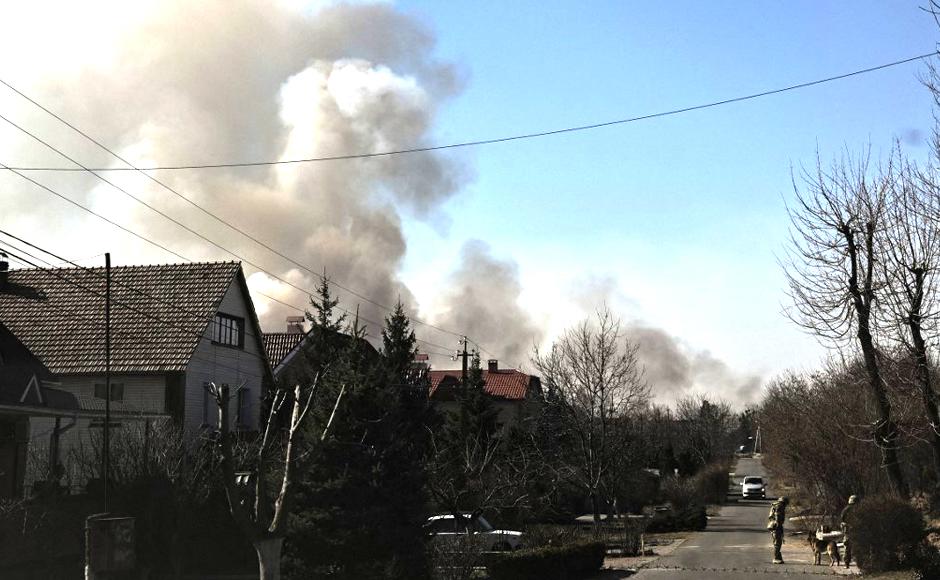 Soldados ucranianos controlan un puesto de control mientras se eleva el humo después de un bombardeo en la ciudad de Novi Petrivtsy, al norte de Kiev.