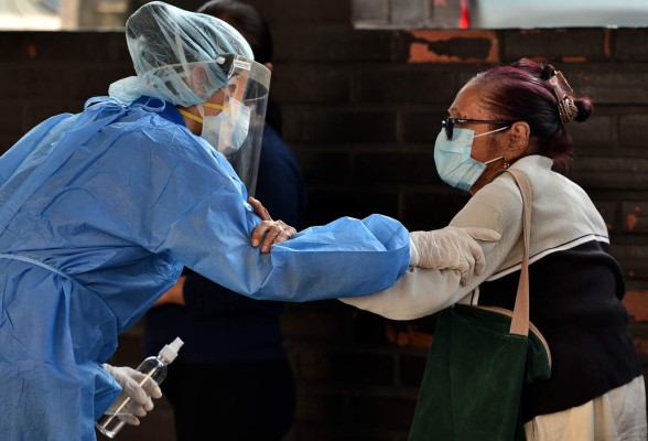 A nurse in PPE (personal protective equipment) attends an elderly woman at the emergency room of the Social Security Institute of Honduras, during the pandemic of the novel coronavirus, COVID-19, in Tegucigalpa, on April 1, 2020. - The World Health Organization said Wednesday it was concerned about the recent 'rapid escalation' and global spread of the new coronavirus pandemic. (Photo by Orlando SIERRA / AFP)