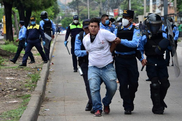 Honduran riot police members arrest a demonstrator during a protest of taxi and mototaxi drivers demanding food and an economic aid from Juan Orlando Hernandez government, in Tegucigalpa, on May 27, 2020, amid the new coronavirus, COVID-19, pandemic. - Taxi and mototaxi drivers block the access to the capital, alleging that they face a difficult economic situation due to the confinement by the Covid-19. According to official reports 4401 people have been infected and 188 have died from COVID-19 in Honduras so far. (Photo by ORLANDO SIERRA / AFP)