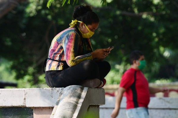 A woman wearing a face mask uses his cellular phone at a square amid the 'absolute curfew' ordered by the Honduran government to slow the spread of the new coronavirus, COVID-19 in Tegucigalpa on April 4, 2020. - The number of people infected with COVID-19 reached 264 and 15 deaths, in the Central American country. (Photo by ORLANDO SIERRA / AFP)